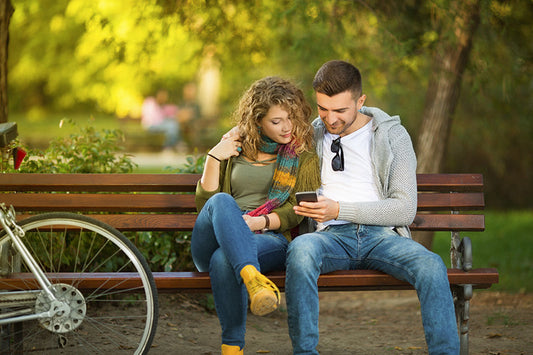 Pärchen auf Parkbank mit Smartphone