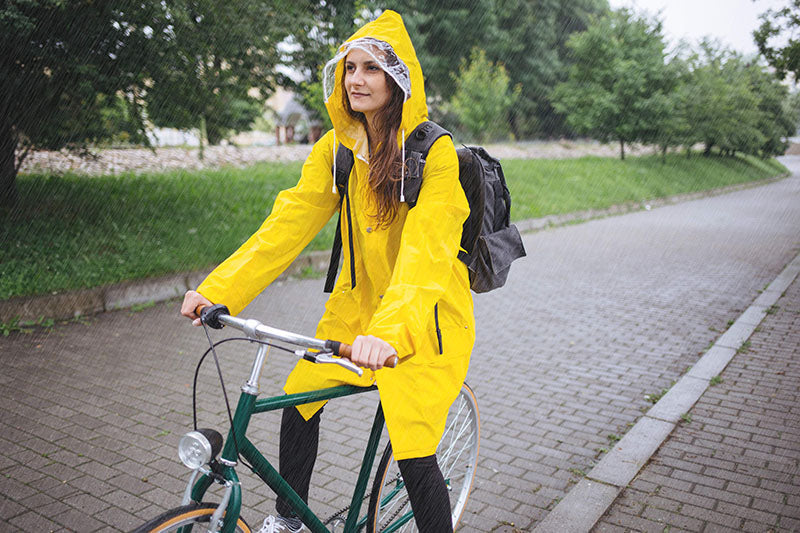Frau mit gelber Regenjacke auf Fahrrad