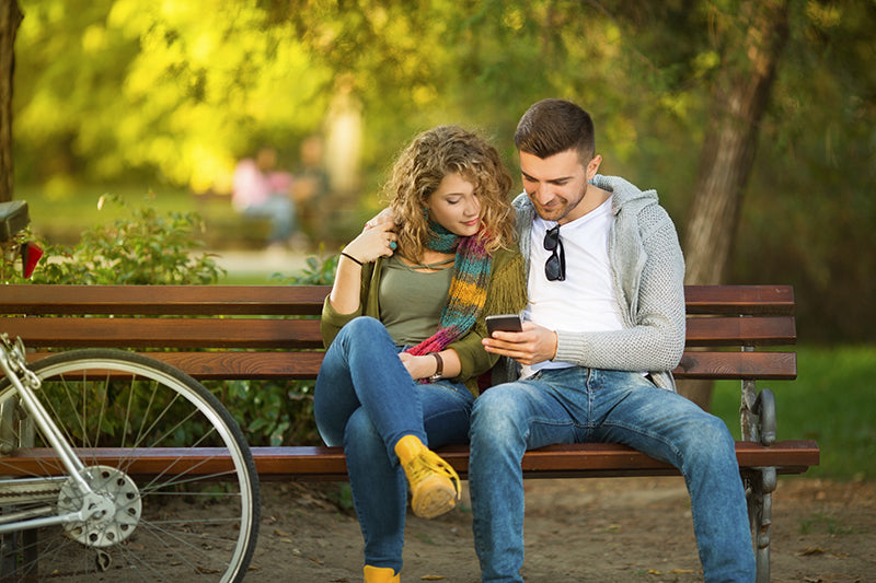 Paar auf Bank mit Smartphone und Fahrrad